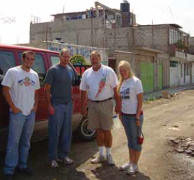 Assistant risk control manager Brandon Joy, left, tours one of Mexico City’s slums with other Transformación Urbana volunteers. They are standing in front of a red truck