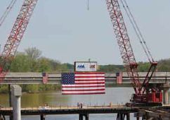 Photo of the Yadkin bridge project. The American flag hangs between to cranes