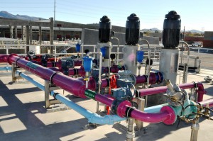photo of multi colored pipes at a water reclamation facility. There are blue, magenta, cyan and aqua pipes.