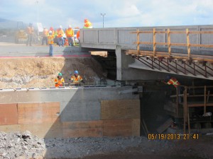 Photo of construction workers in orange vests at a bridge construction site