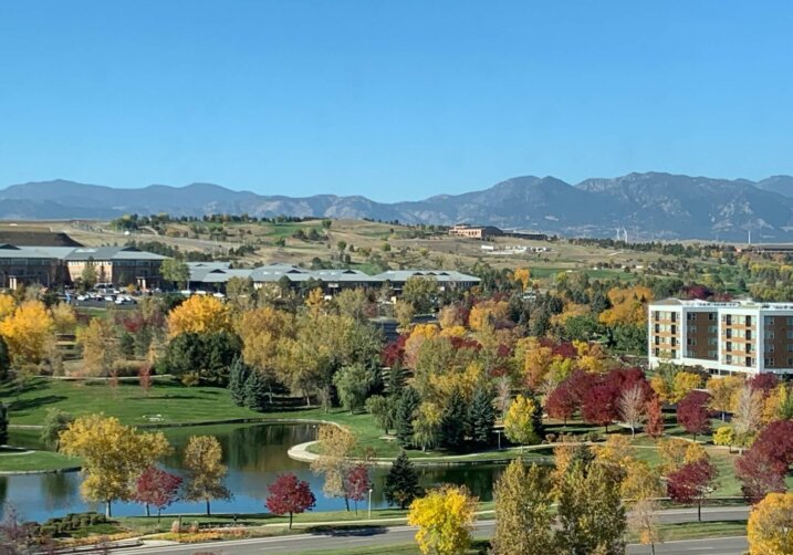 view of the flatirons from Broomfield office with colorful trees in fall